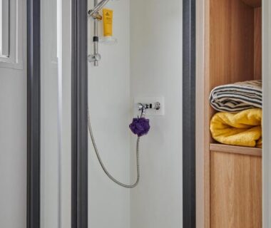 Cabine de douche et étagères avec serviettes dans le bungalow du Slow Village Breizh Légendes