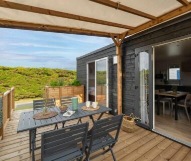 Terrasse en bois avec table et chaises face aux dunes au Slow Village Breizh Légendes