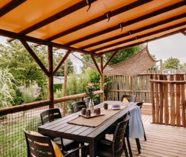 Terrasse couverte avec table et chaises donnant sur jardin au Slow Village Pornic