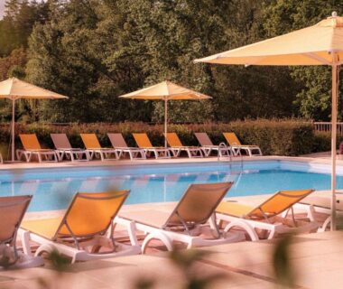 Piscine bordée de transats et parasols au Slow Village Séveilles Périgord