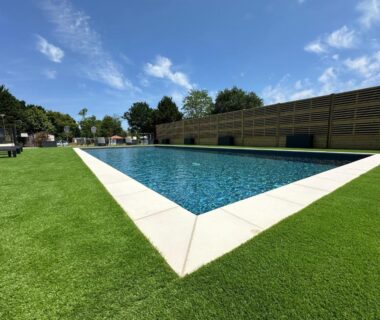 Bord de piscine extérieure avec pelouse au camping Soleil Luna
