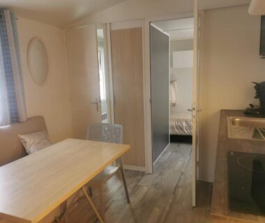 Intérieur avec coin repas kitchenette et chambre visible dans le mobil home Soleil Luna