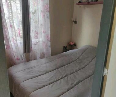 Chambre avec lit double et rideaux fleuris dans le mobil-home Sophie Mobil-home 201