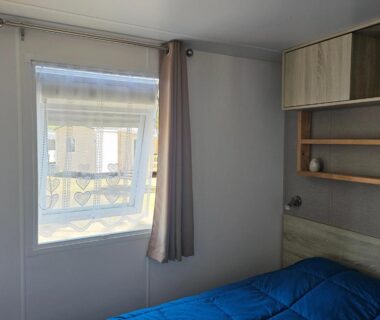 Chambre avec lit et fenêtre dans le mobil home Sous les Pins