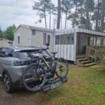 Extérieur du camping avec voiture et vélos devant le mobil-home Sous les Pins