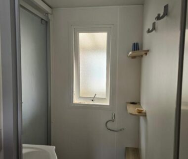 Salle de bains avec lavabo fenêtre étagères dans le MH familial Sous les Pins