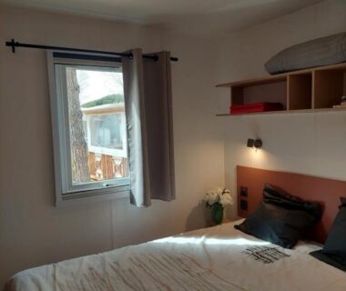 Chambre avec lit double fenêtre et étagères dans le Spacieux mobilhome climatisé 4 P au GRAU du Roi en Camargue