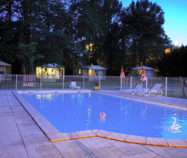Piscine extérieure éclairée entourée de mobil homes au Studiotel premium 2 personnes