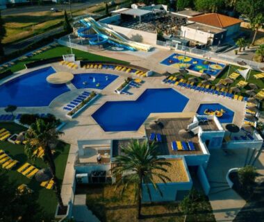 Piscines extérieures avec toboggans transats et palmiers au Sun Sea camping le Bosc