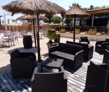 Terrasse lounge extérieure avec canapés et parasols en paille au Sun Sea camping le Bosc