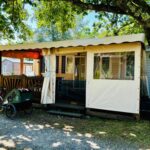 Terrasse couverte sous arbre avec vélos et chaises du Superbe Mobilehome 3 ch climatisé tout confort
