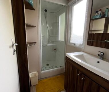 Salle de bains avec douche vitrée et lavabo dans le Superbe Mobilehome 3 ch climatisé tout confort