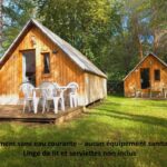 Chalets en bois sur pelouse avec terrasse au TRAPPEUR Les Chalets du lac Belcaire