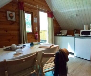 Intérieur en bois avec coin repas et kitchenette dans le chalet TRAPPEUR Les Chalets du lac Belcaire