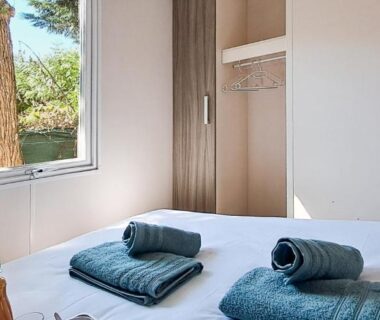 Chambre avec lit, serviettes roulées et fenêtre dans le Temps Suspendu