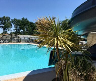 Piscine extérieure avec toboggan et palmier au camping Temps Suspendu