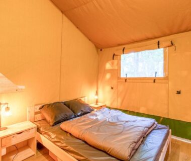 Intérieur de tente avec lit double et éclairage chaleureux dans la Tente Lodge 8 personnes