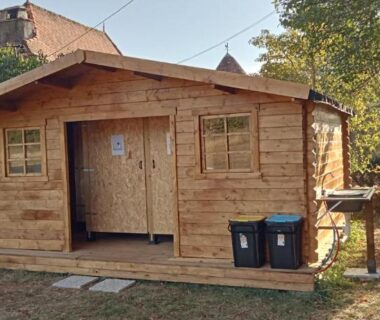 Façade de chalet en bois avec terrasse et poubelles à la Tente Perchée Kenya MAS DE BOUZOU