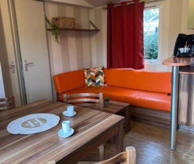 Salon avec canapé orange et table à manger dans le mobil-home Terra Cosy