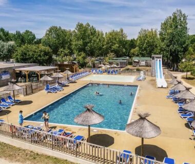 Piscine extérieure avec toboggan et parasols au camping The Spot - 200m de la Plage
