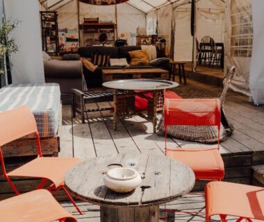 Terrasse en bois avec chaises orange et salon sous tente au The Spot 200m de la Plage