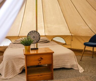 Intérieur de tente glamping avec lit et table de chevet dans le camping The Spot – 200m de la Plage