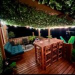 Terrasse en bois éclairée avec table haute et banquette dans le Tiki House M-Home-Climatisé Belle parcelle