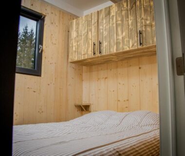Chambre en bois avec lit et fenêtre dans le Tiny House du Camping Les Granges Bas