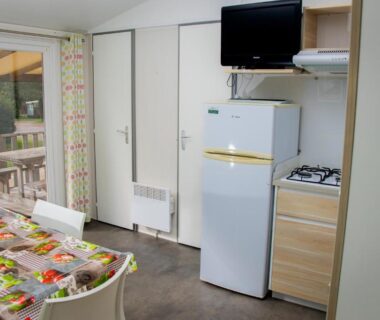 Intérieur kitchenette avec coin repas et terrasse visible dans le mobilhome Camping Les Granges Bas