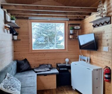 Intérieur en bois avec canapé télévision et fenêtre dans la Tiny House – Cottages – Mobilhomes – Camping Les Granges