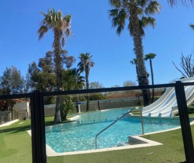 Piscine et toboggan entourés de palmiers au Tiny House Mobilhome 6 personnes au Port de Vendres plage