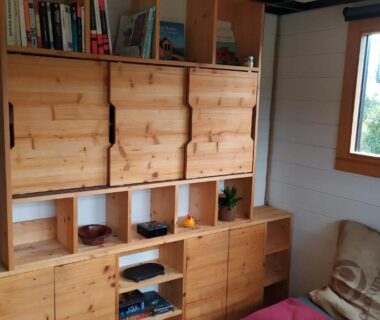 Intérieur avec meubles de rangement en bois et canapé dans la Tiny House de la Côte Roannaise