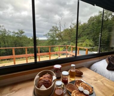 Table en bois avec petit déjeuner près de la fenêtre dans la Tiny house romantique avec bain nordique