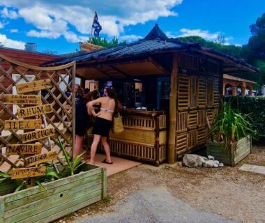 Kiosque bar en bois avec clients et végétation au camping Tribord Dix Neuf