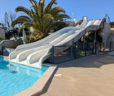 Piscine extérieure avec toboggans et palmier au camping Ty Névez