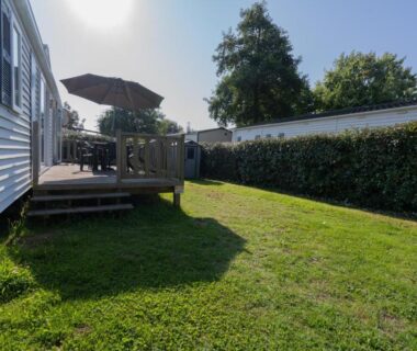 Terrasse en bois avec parasol et pelouse du mobil-home Ty Névez