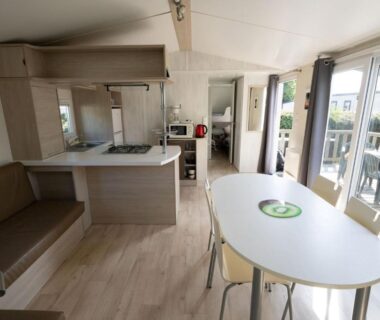 Intérieur de mobil-home avec kitchenette table et terrasse visible du Ty Névez