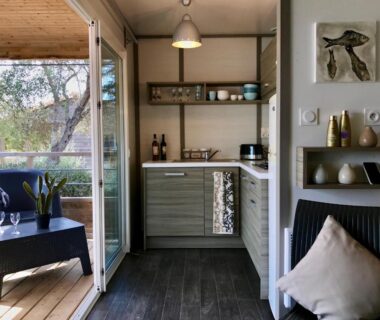 Terrasse en bois avec table et kitchenette visible dans l'hébergement U FARNIENTE