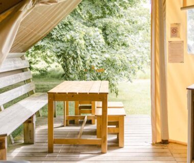 Terrasse couverte en bois avec table et bancs dans Un éco-camping en Vendée