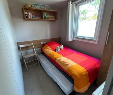 Chambre avec lit simple et tiroir-lit sous la fenêtre dans le camping Un été au Cap Ferret
