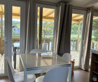 Séjour avec table à manger et chaises donnant sur terrasse vitrée dans Un été au Cap Ferret