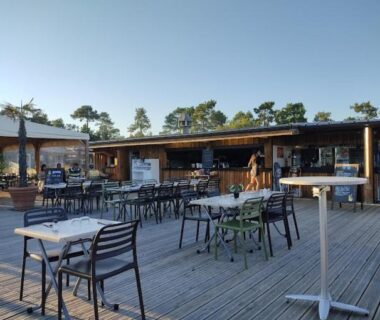 Terrasse en bois avec tables et chaises au camping Un été au Cap Ferret