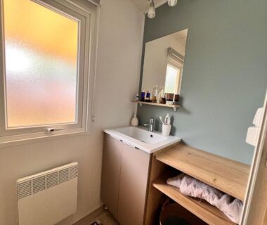 Salle d'eau avec lavabo miroir fenêtre et rangement dans le bungalow Un toit sur le bassin bungalow