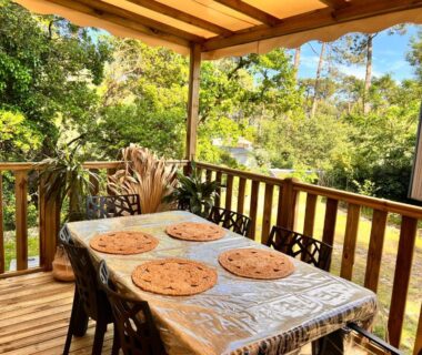 Terrasse couverte avec table et sets de table dans le bungalow Un toit sur le bassin