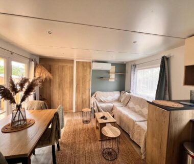 Salon lumineux avec canapé et coin repas dans le bungalow Un toit sur le bassin