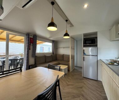 Intérieur avec kitchenette et terrasse donnant sur le bassin du bungalow Un toit sur le bassin au camping Les Viviers