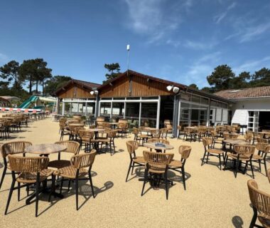 Terrasse extérieure avec nombreuses tables et chaises au camping Un toit sur le bassin les Embruns