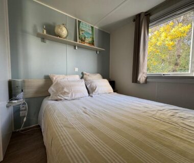 Chambre avec lit double et fenêtre donnant sur la végétation dans le camping Un toit sur le bassin les viviers