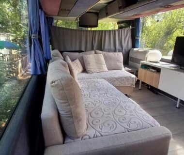 Intérieur du bus avec canapé et grande baie vitrée de l'Unique et Insolite Bus Iliade