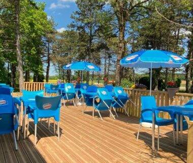 Terrasse en bois avec chaises et parasols à l'Unique et Insolite Bus Iliade